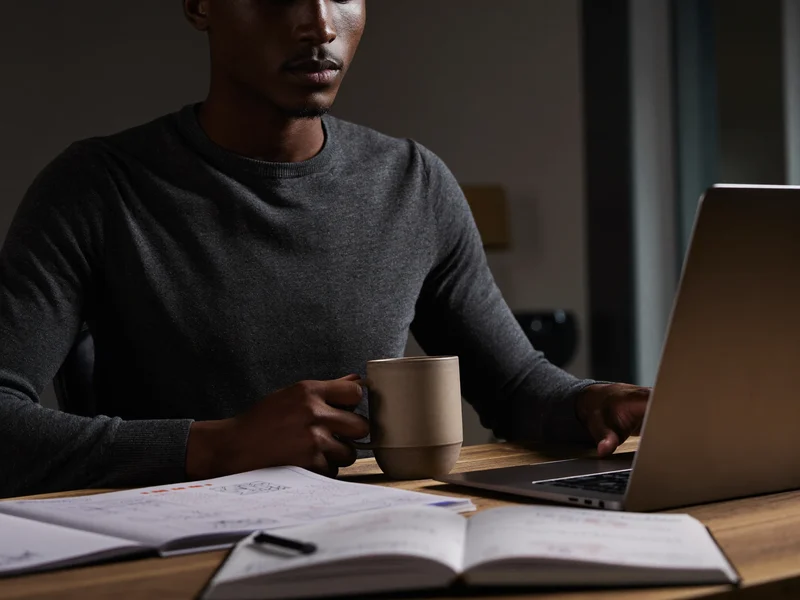 Tvůrce u uklizeného stolu s notebookem, rukopisným zápisníkem a keramickým hrnkem